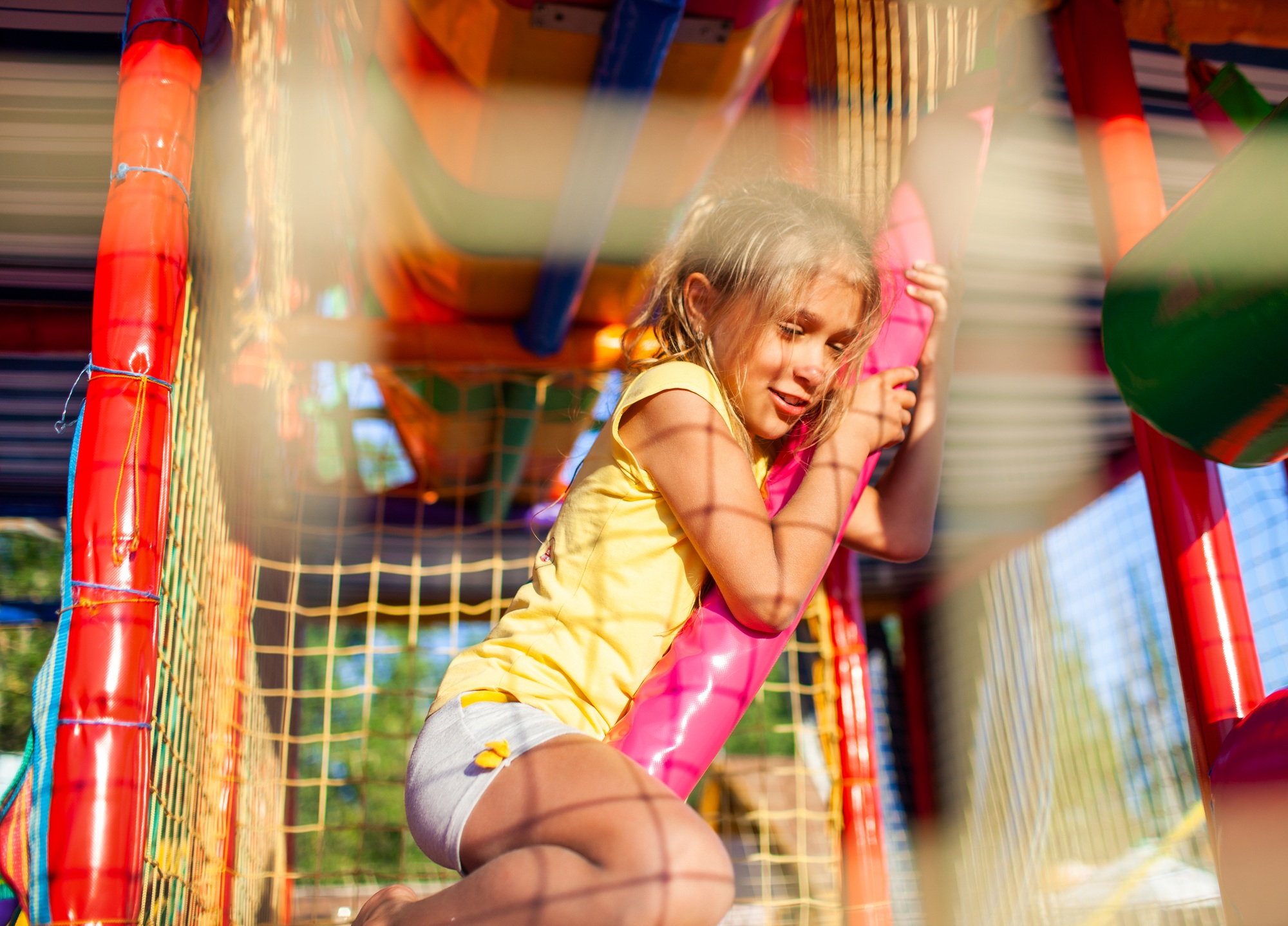 Funny tear-stained girl sits on a colored mat in a large entertainment center with colorful equipmen