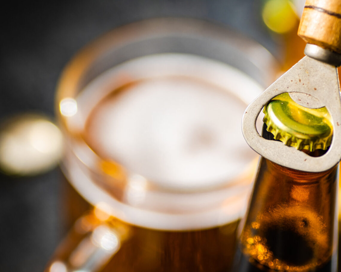 Beer bottle and opener. On rustic background.